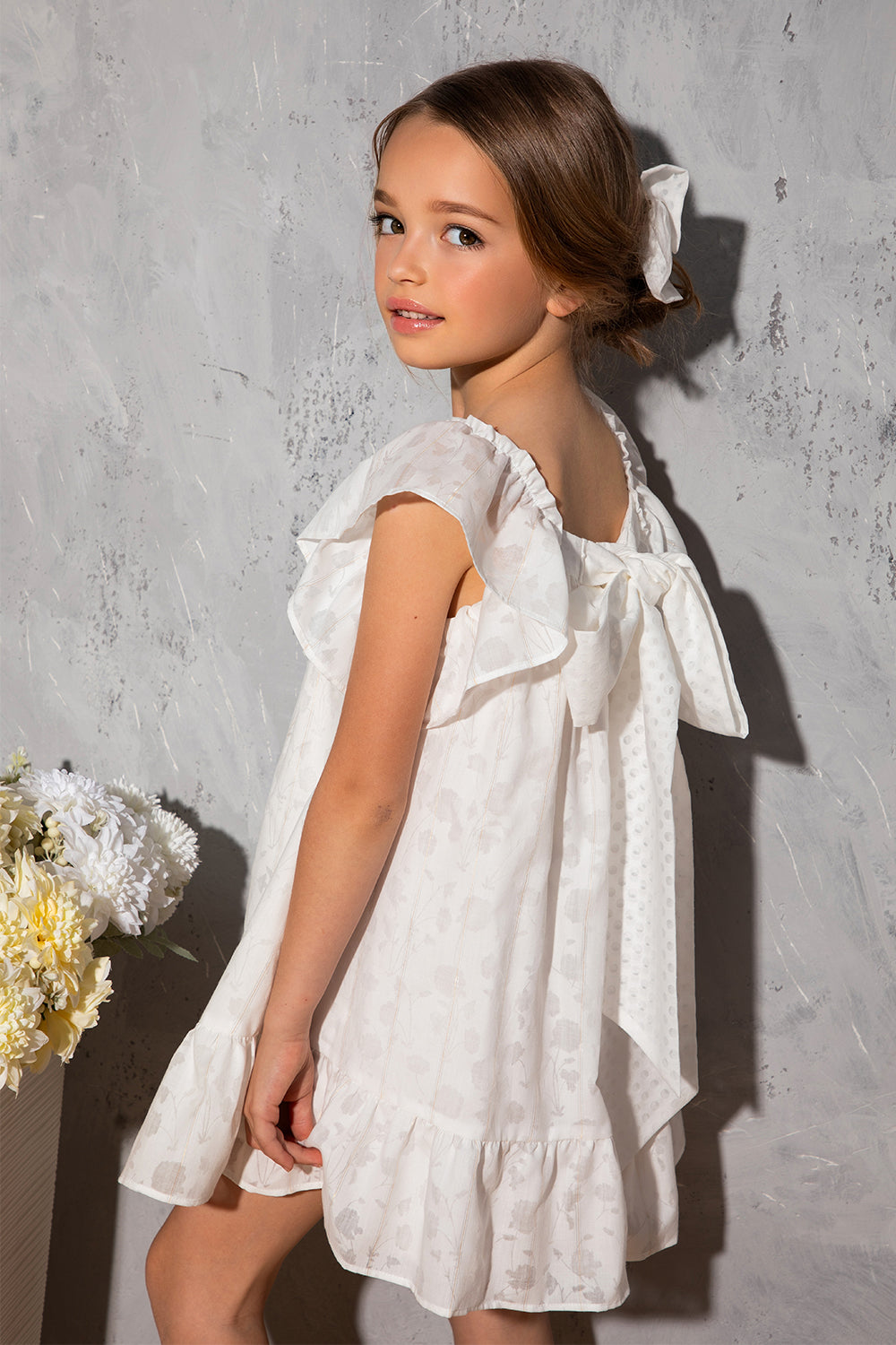 White flowy dress with dots, frills and big bow on the back