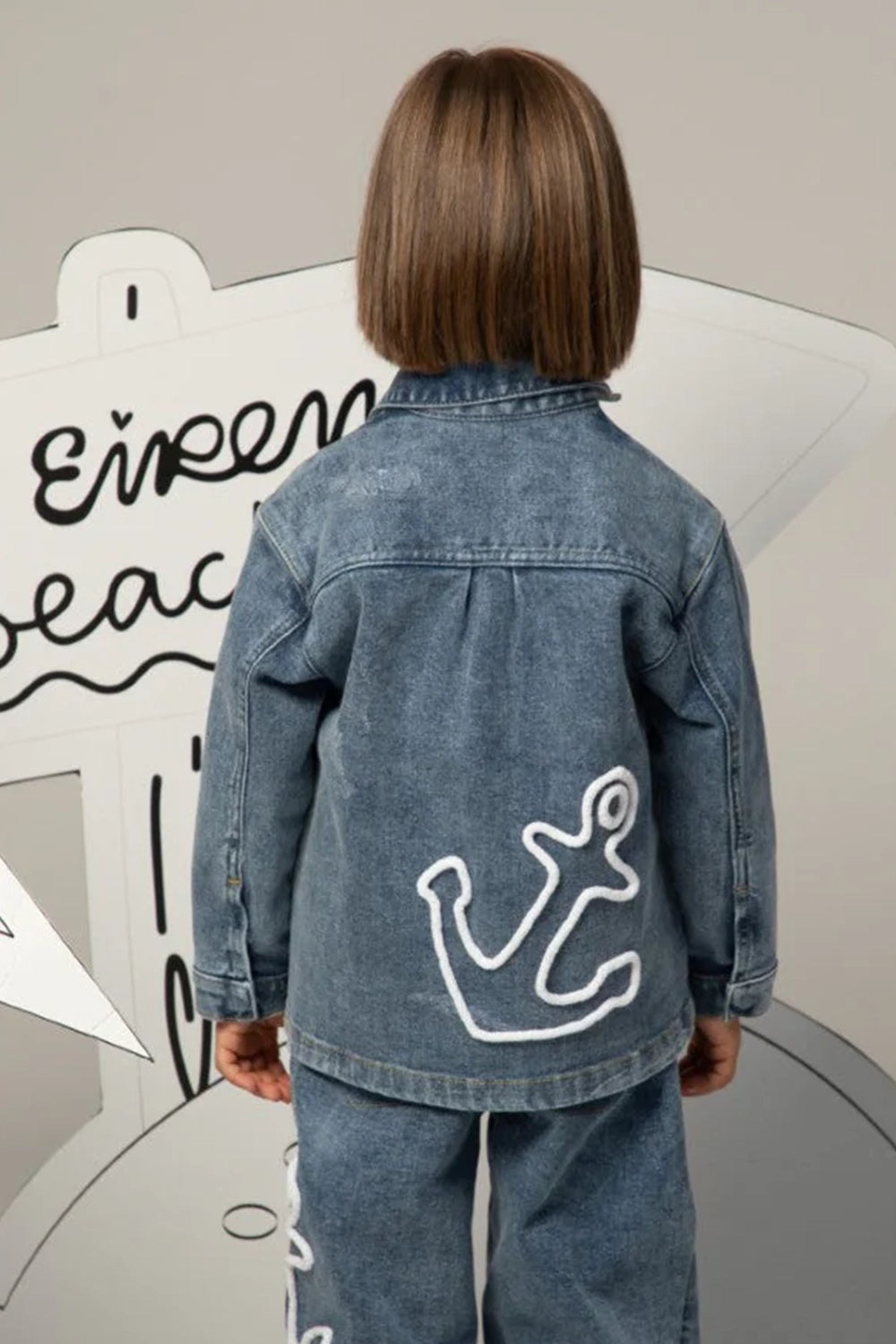 Denim jacket with classic collar, flap pockets, and colorful embroidered patch on the front