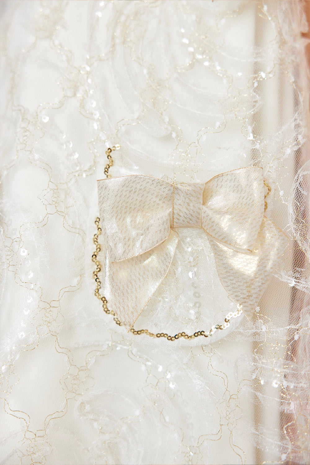 Ivory A-line lace dress with gold shoulder bows and pocket bow details