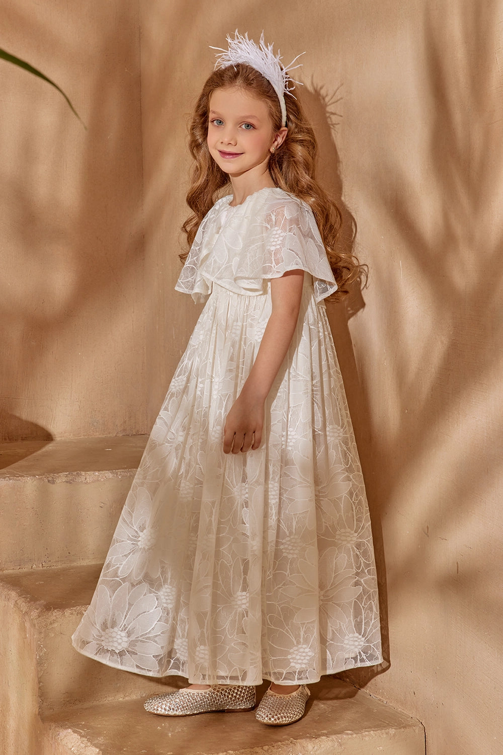 Off-white floral lace dress with flutter sleeves and cape, shimmering bow