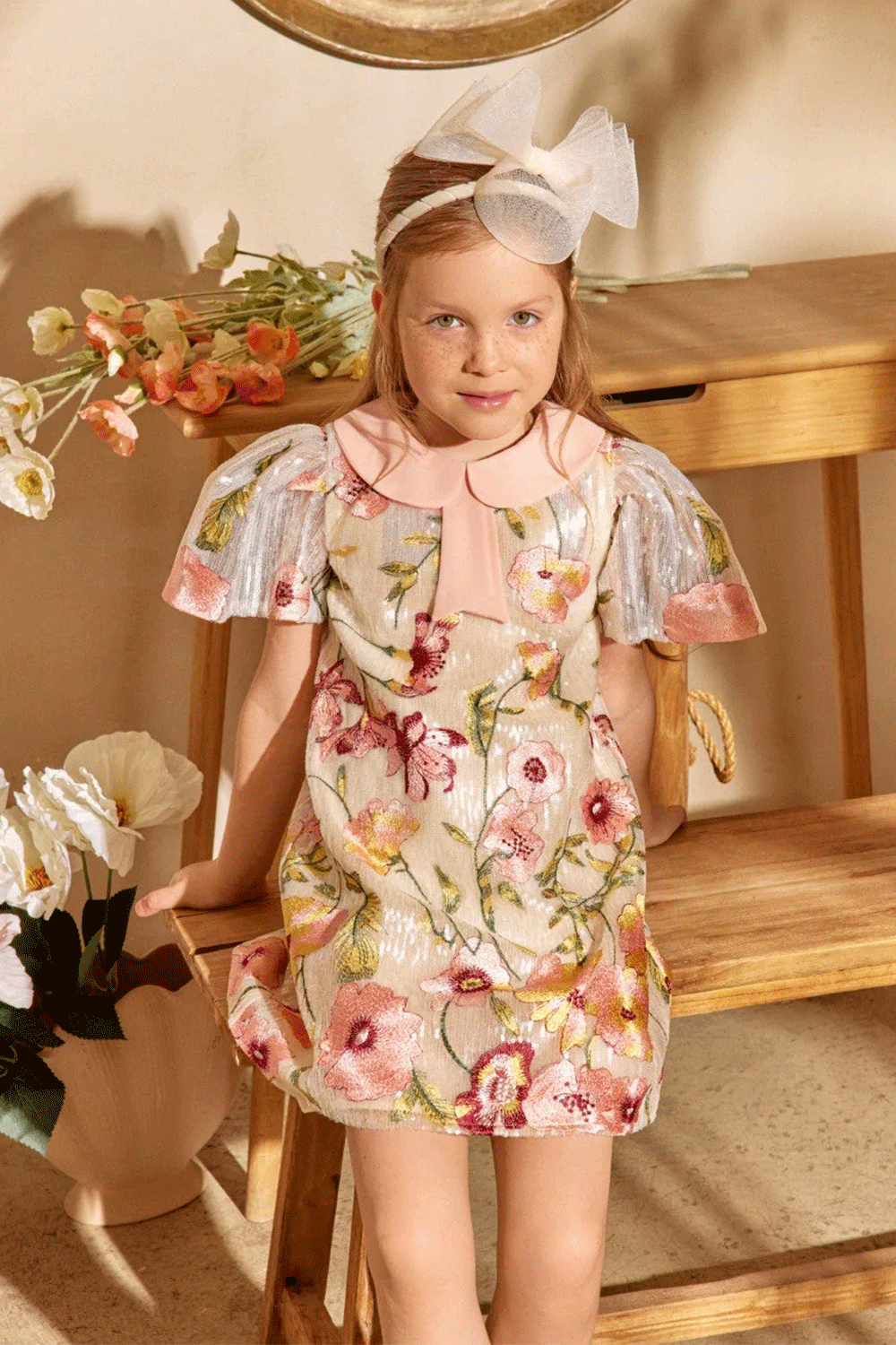 Ivory sequin dress with floral embroidery, pleated metallic sleeves, and a soft pink peter pan collar with bow detail