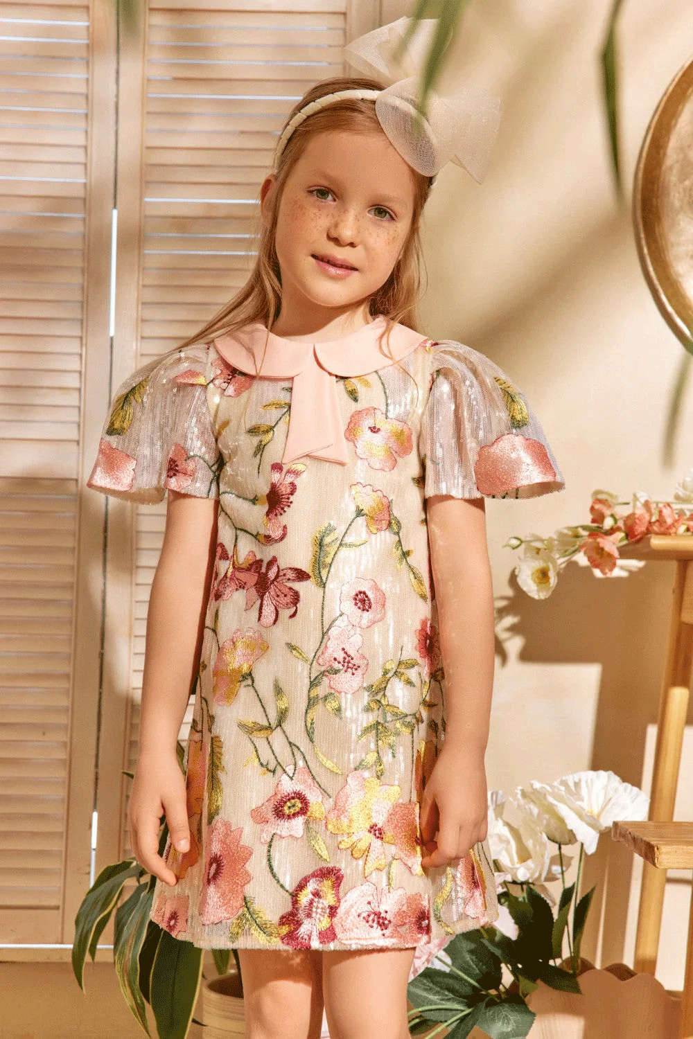 Ivory sequin dress with floral embroidery, pleated metallic sleeves, and a soft pink peter pan collar with bow detail