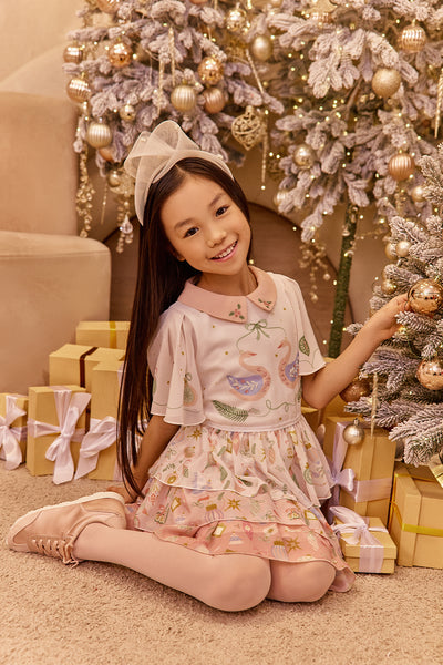 Young girl in a festive setting with Christmas decorations and presents.