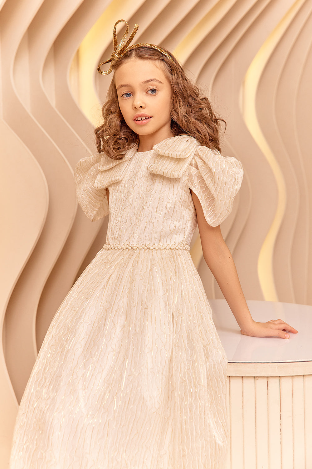 فستان من العاج وخيوط الذهب مع أقواس على الكتف