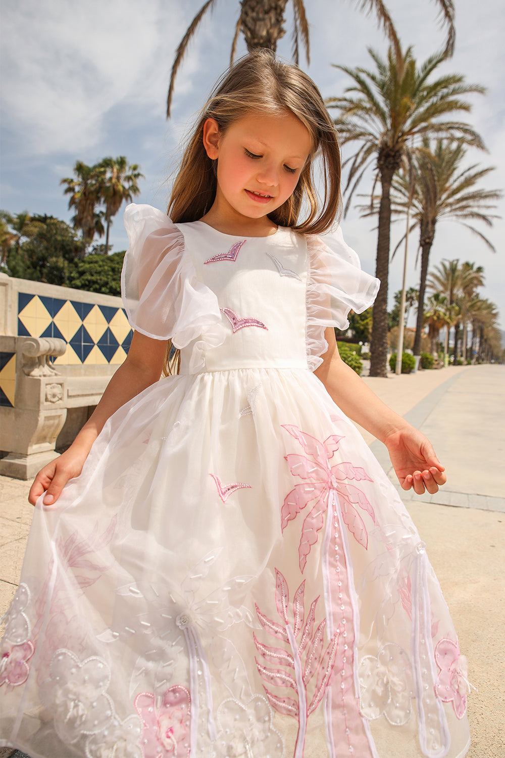 White organza dress with frilled sleeves, hand appliqué of embellished pink and white palms, flowers and birds