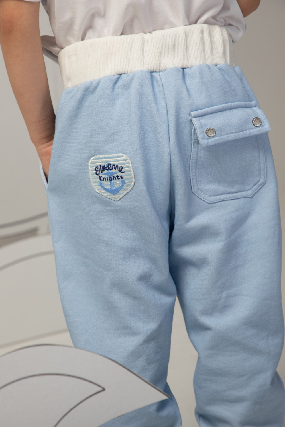 Light blue pants with white striped cuffs and a small sailboat print motif on the leg
