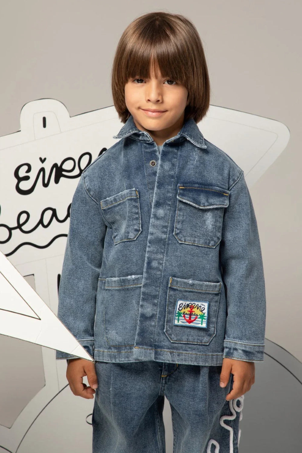 Denim jacket with classic collar, flap pockets, and colorful embroidered patch on the front
