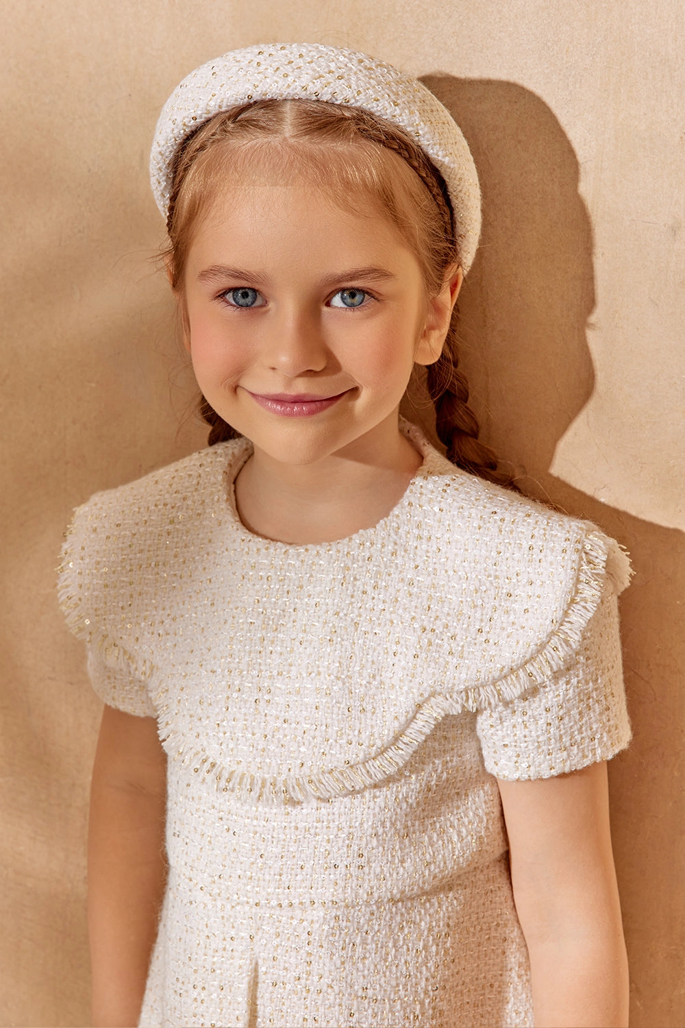 فستان أبيض أنيق من التويد ذو ثنيات أمامية وحواف مزينة بشراشيب