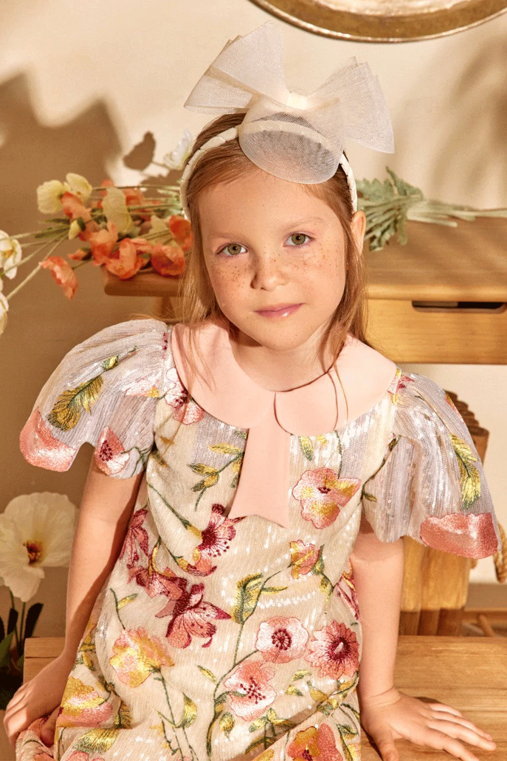 Ivory sequin dress with floral embroidery, pleated metallic sleeves, and a soft pink peter pan collar with bow detail