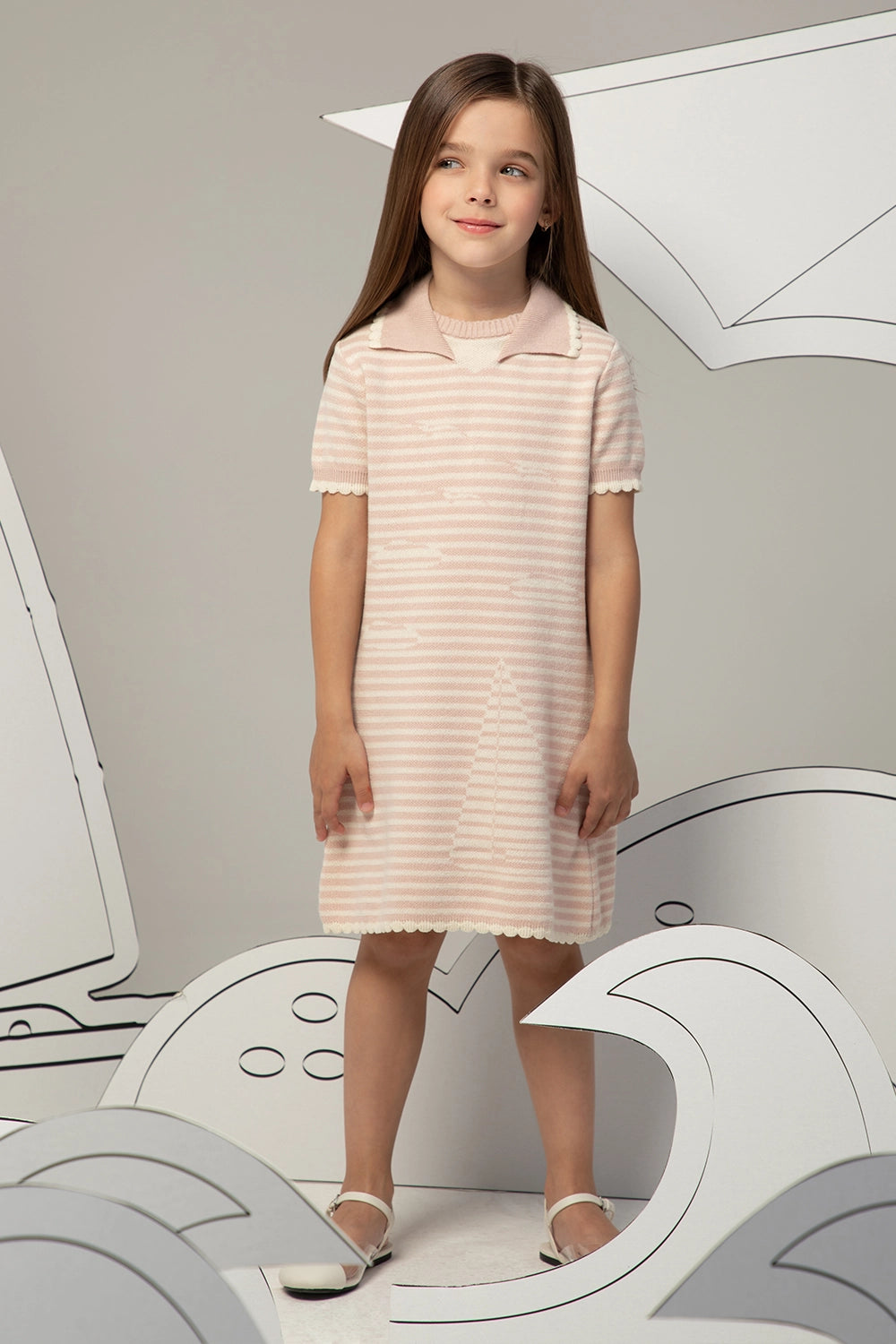 فستان محبوك مخطط باللونين الوردي الفاتح والأبيض بأكمام قصيرة وتفاصيل عند الياقة ونقشة قارب شراعي دقيقة.